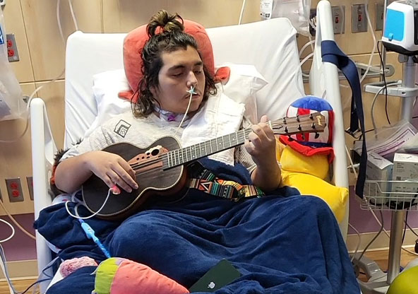 boy playing guitar on hospital bed